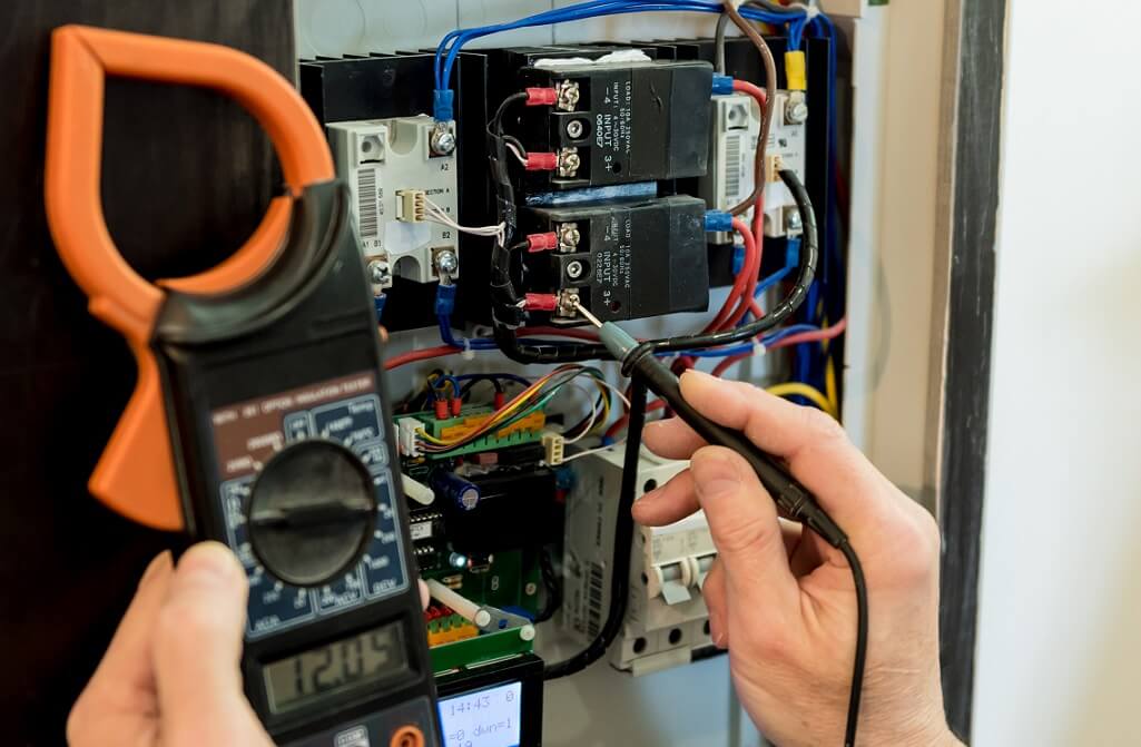 électricien qui contrôle la tension grâce à un multimètre