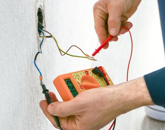 électricien qui mesure la tension d'un câble électrique